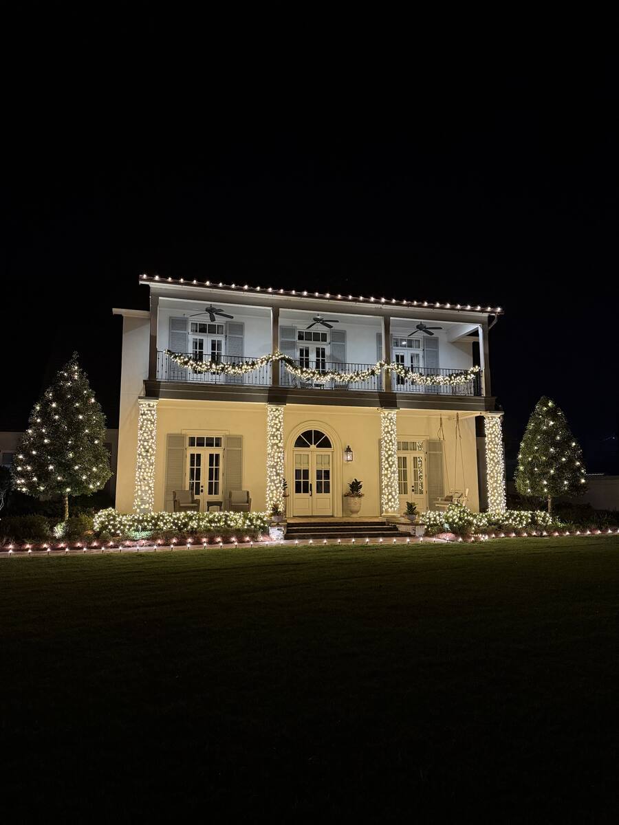 Two-story Baton Rouge home lit by Tiger Christmas Creations: roofline, wrapped columns, balcony garland and two lit trees